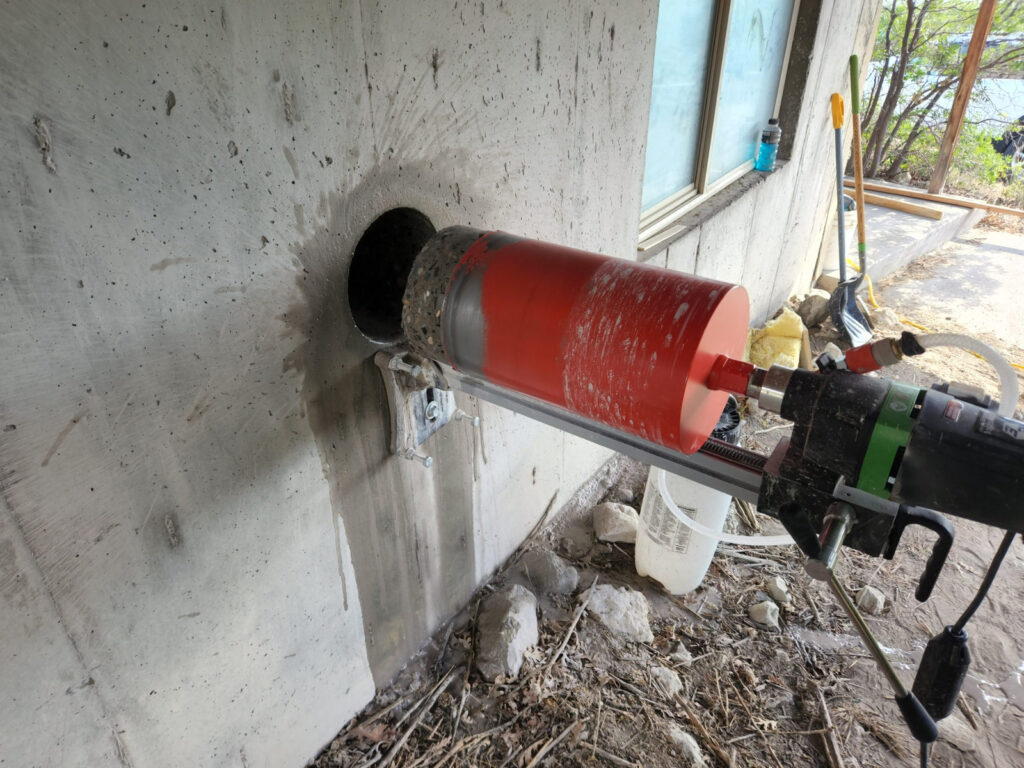 Horizontal concrete core drilling through an exterior foundation wall in Utah using a mounted diamond core drill